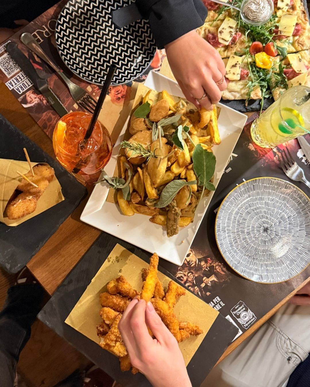Aperitivo visto dall'alto: patate con salvia, fritti, pinsa e uno spritz