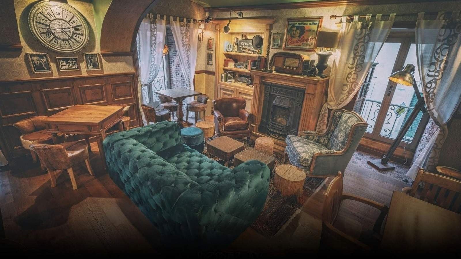 La sala del Lobelix: divano Chesterfield in velluto verde, camino e arredi d'epoca