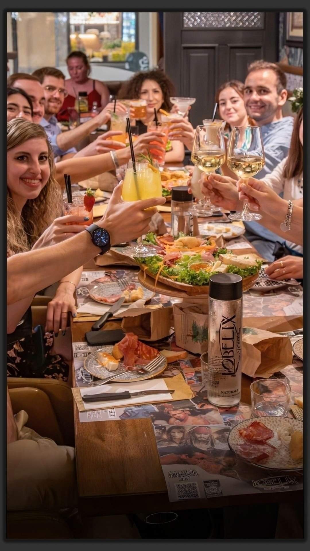 Amici che brindano a una lunga tavolata apparecchiata per la cena